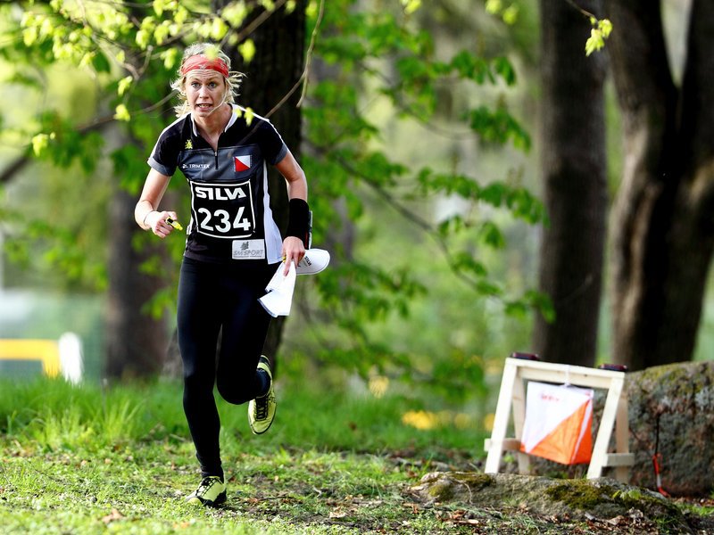 A female orienteer out and running in the forest.