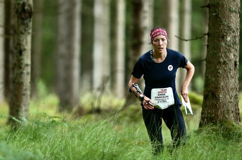 Female orienteer competing in the forest.