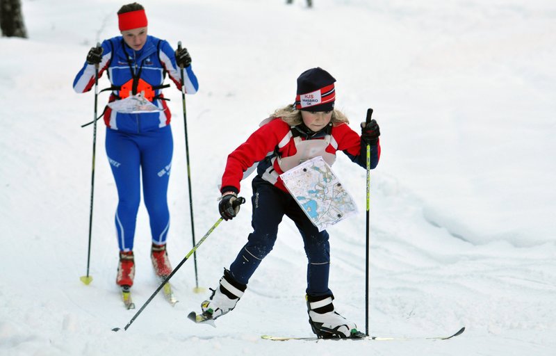 A girl ski orienteering with the map holder around her neck.